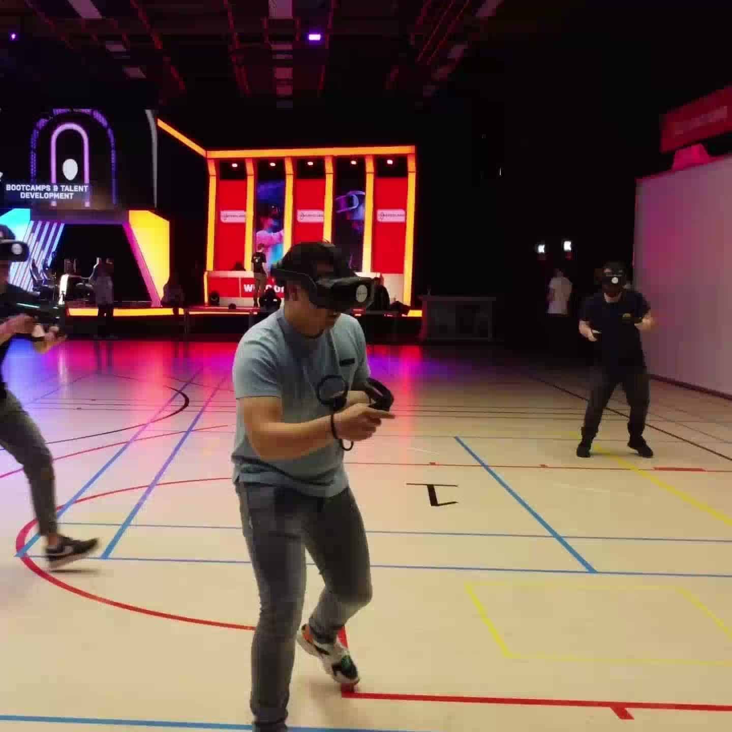 A player wearing a VR headset in a sports hall lit up as a virtual arena